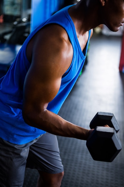 Athlète masculin exerçant avec haltère en studio de remise en forme