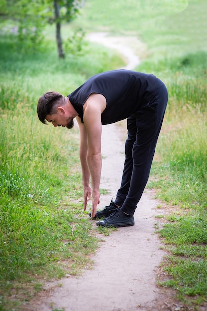 Athlète masculin faisant des étirements dans la nature