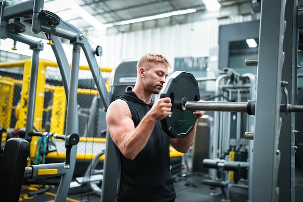 Athlète masculin faisant de l'exercice dans la salle de gym soulever des poids en tirant des articulations