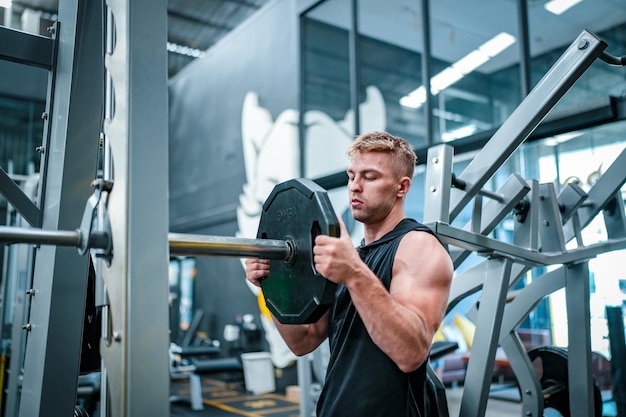 Athlète masculin faisant de l'exercice dans la salle de gym soulever des poids en tirant des articulations