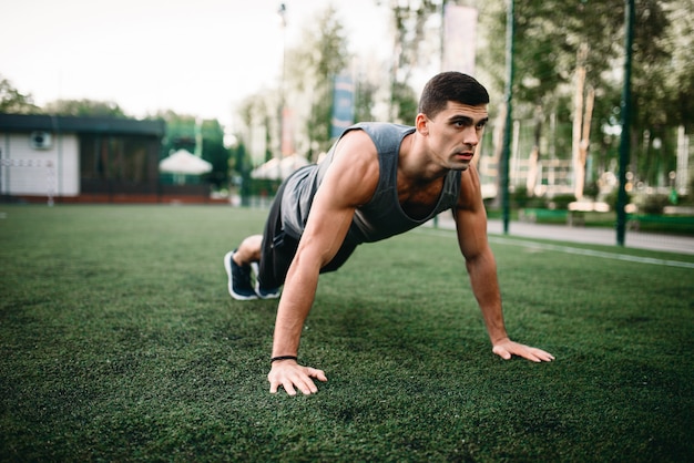 Athlète masculin faisant des exercices de push-up sur l'entraînement de fitness en plein air. Sportif sur la formation dans le parc