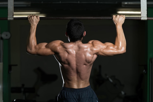 Athlète masculin faisant des tractions dans la salle de gym