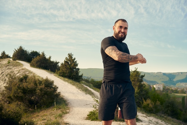 Athlète masculin s'échauffant avant de commencer à courir dans les montagnes