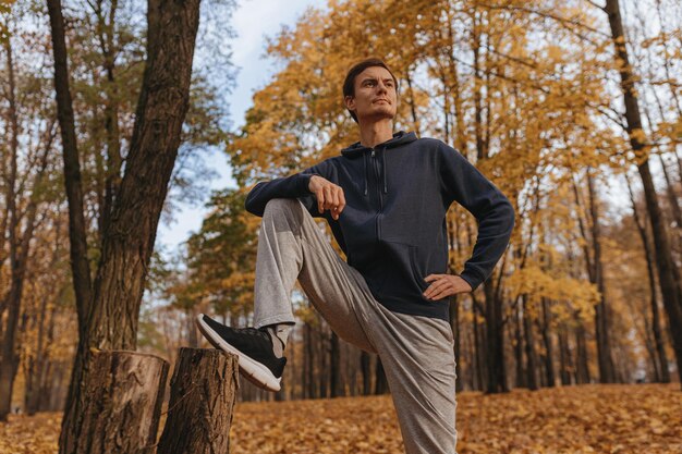 Athlète masculin souriant étirant les jambes et s'échauffant