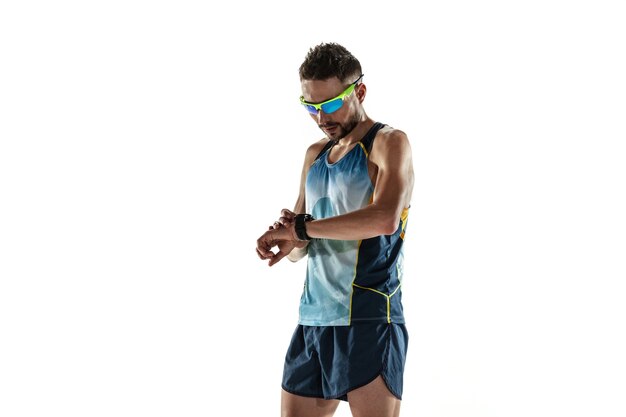 Athlète masculin de triathlon en cours d'exécution isolé sur fond de studio blanc. Jogger en forme de race blanche, entraînement de triathlète portant des équipements de sport. Concept de mode de vie sain, sport, action, mouvement. Contrôle du temps.