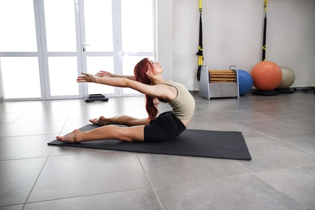 Athlète modèle faisant du yoga dans la salle de gym Fille flexible faisant des exercices pour la colonne vertébrale Sport