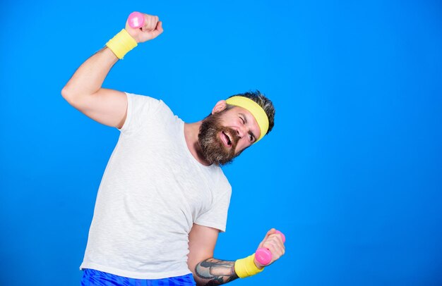 Athlète motivé Entraînement sportif avec haltères fond bleu Améliorez vos muscles Utilisez des poids ou des haltères Athlète barbu exerçant des haltères Entraînement d'athlète avec haltères minuscules