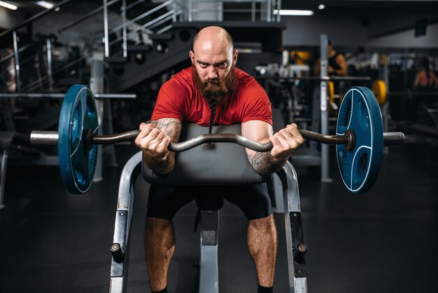 Athlète musclé, faire de l'exercice avec haltères dans la salle de gym.