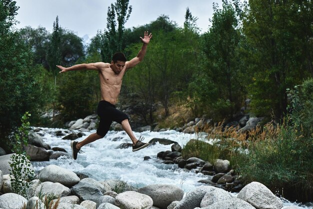 Un athlète musclé kazakh s'entraîne et s'exerce au bord de la rivière dans la nature. Beau asiatique fait de l'exercice physique extrême à l'extérieur