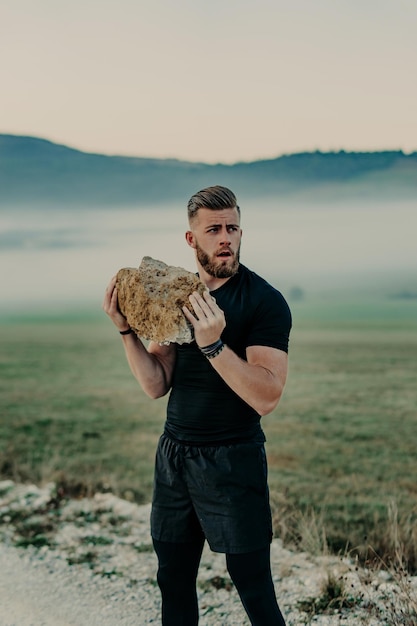 Un athlète musclé s'entraîne et s'exerce avec une grosse pierre