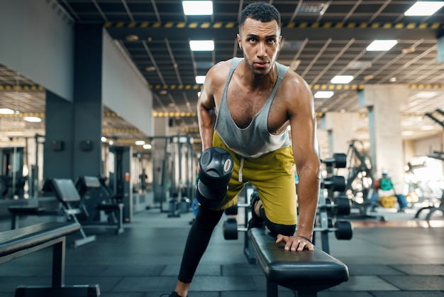 Athlète musclé en vêtements de sport faisant de l'exercice avec des haltères sur le banc, s'entraînant en salle de sport. Entraînement dans un club de sport, mode de vie sain