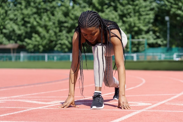Une athlète noire se prépare à courir pour établir un nouveau record ou un entraînement cardio quotidien en plein air