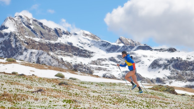 Athlète de piste dans les montagnes en montée avec des bâtons