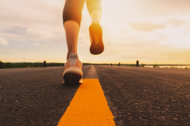 Athlète qui court sur le sentier de la route au coucher du soleil pour s'entraîner au marathon et au fitness. flou de mouvement de femme exerçant à l'extérieur