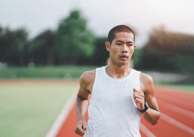 Athlète sportif coureur s'entraînant sur la voie du stade le matin Coureur homme portant un gilet blanc pour s'entraîner à courir se préparer à la course de compétition Concept sportif