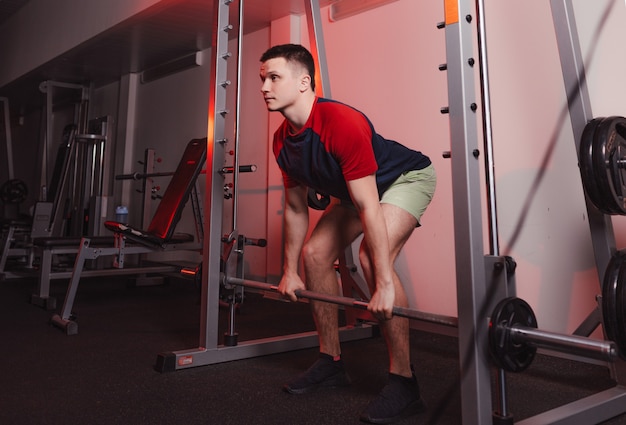 L'athlète tient une barre dans ses mains tout en se préparant à s'accroupir. musculation dans la salle de gym