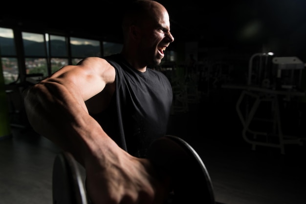 Athlète travaillant sur les épaules dans un gymnase Curls de concentration d'haltères