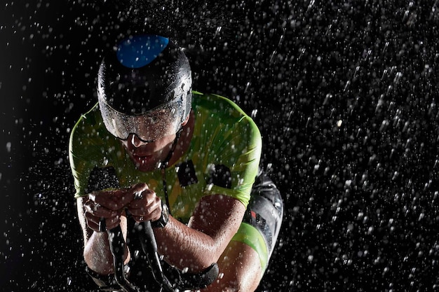 athlète de triathlon à vélo rapide sur une nuit de pluie