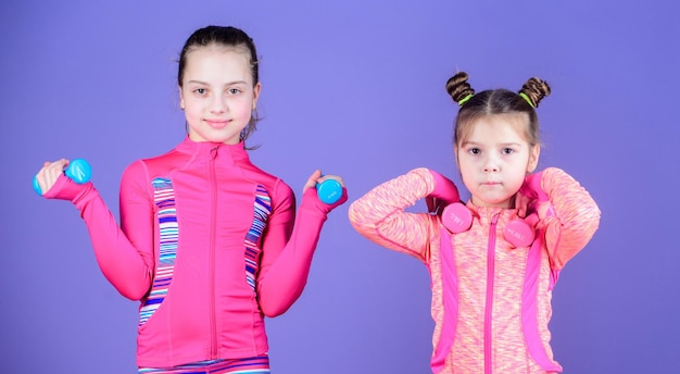 Athlètes adorables Les petits enfants développent leur forme physique Les petites filles aiment s'entraîner avec des poids Sœurs mignonnes faisant des exercices de fitness avec des haltères Sport et fitness pour les enfants