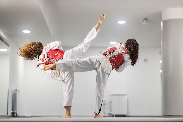 Des athlètes de taekwondo en doboks s'entraînent au combat et à l'attaque dans une école d'arts martiaux