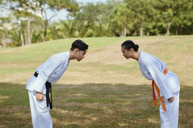 Des athlètes de taekwondo s'inclinent l'un face à l'autre.