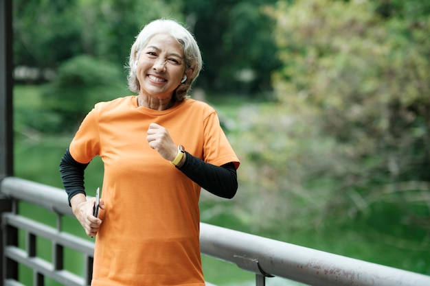 Photo athletic senior femme exécutant le jogging en plein air dans le parc.