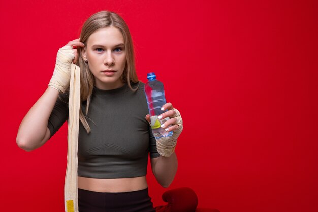 Athlétique jeune femme boit de l'eau après l'entraînement de boxe