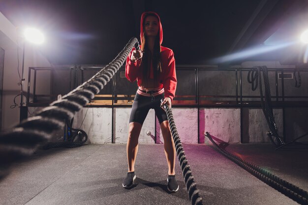 Athlétique jeune femme faisant des exercices avec une corde en plein air.