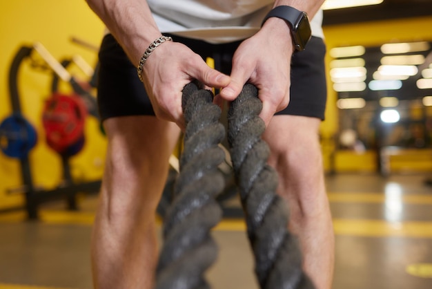 Athlétique jeune homme avec une corde de bataille, faire des exercices dans la salle de gym de formation fonctionnelle