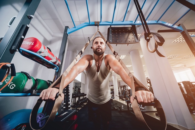 Athlétique jeune homme s'entraînant avec des sangles de fitness trx.