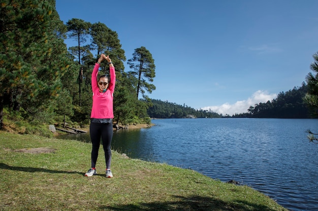 Photo atleta estirando despues de correr a la orilla de un lago