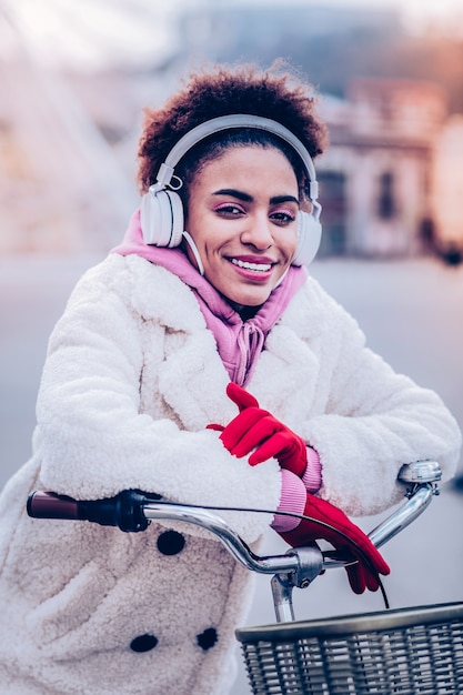 Une atmosphère détendue. Incroyable jeune femme gardant le sourire sur son visage alors qu'il était assis sur son vélo