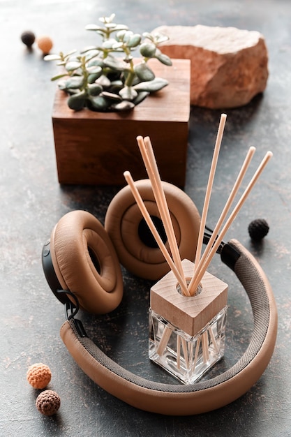 Atmosphère relaxante de bien-être avec musique et aromathérapie image aux tons rétro Écouteurs assainisseur fait main avec diffuseur de bâtons de bambou et bouteille en verre de parfum fait maison Petite plante succulente