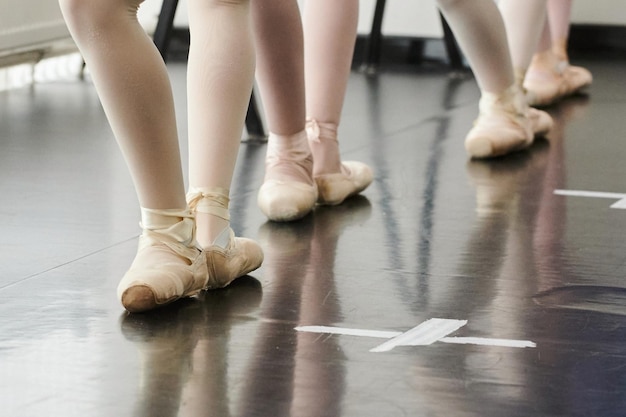 Attacher ses pantoufles avant la représentation Gros plan d'une jeune ballerine en tutu blanc attachant ses pantoufles en position assise