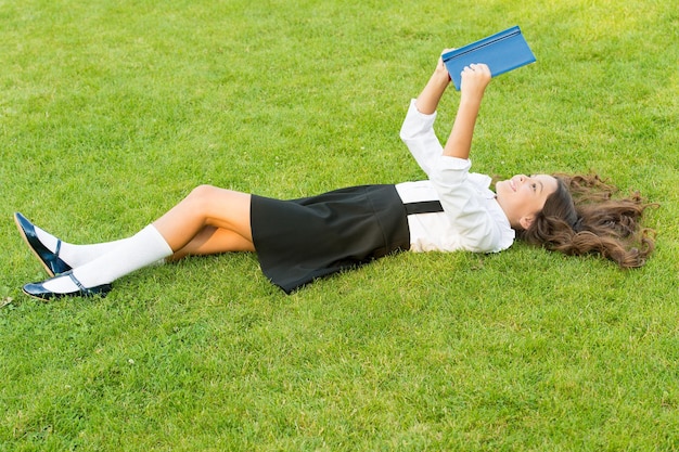 Atteindre l'Excellence. livre de lecture de petite fille. littérature pour enfants. écrire des souvenirs d'enfance. son journal. prendre des notes dans un cahier. retour à l'école. enfant étudie dans le parc. détendez-vous sur l'herbe verte avec un livre.