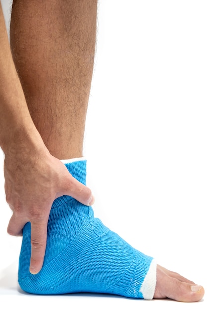 Attelle de cheville bleue. Jambe bandée moulée sur patient de sexe masculin sur fond blanc isolé. Concept de blessure sportive.