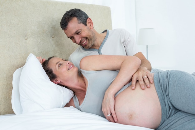 Attend un couple allongé sur le lit et discutant dans leur chambre