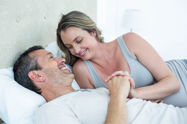 Attend un couple allongé sur le lit et discutant dans leur chambre