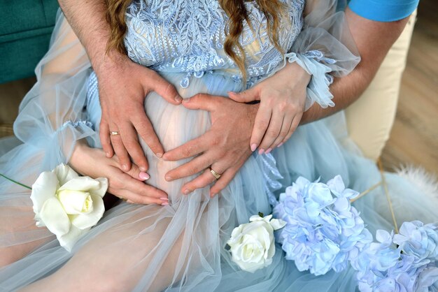 En attendant le bébé Femme enceinte vêtue d'une robe bleue avec un cœur de père les mains sur le ventre