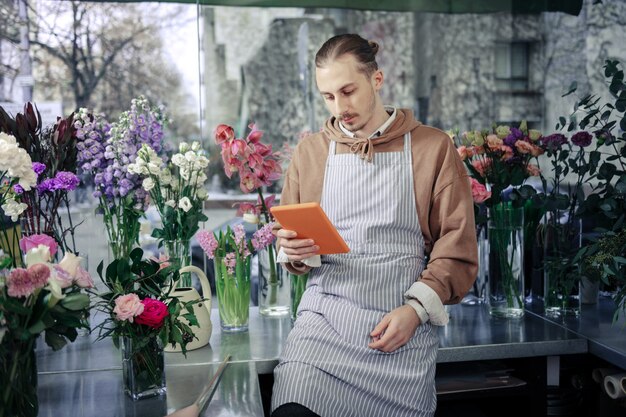 Attends une seconde. Homme sérieux s'inclinant la tête et regardant son gadget