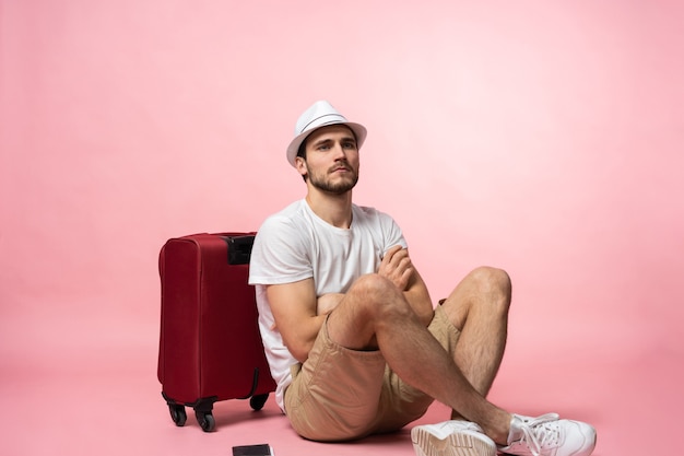 En attente de vol. Voyageur homme assis sur le sol avec valise.