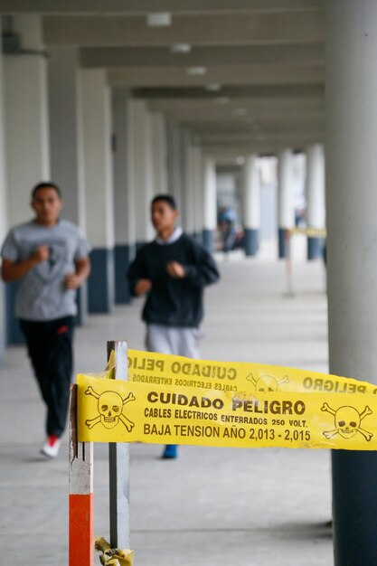 Attention Danger Ruban De Sécurité Jaune Arrière-plan Deux Hommes Flous En Cours D'exécution