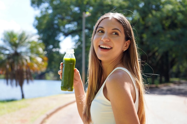 Photo une attirante brésilienne sportive tenant un smoothie vert et un jus de désintoxication à l'extérieur