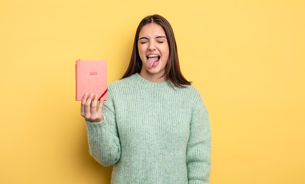 Avec une attitude joyeuse et rebelle, plaisantant et tirant la langue