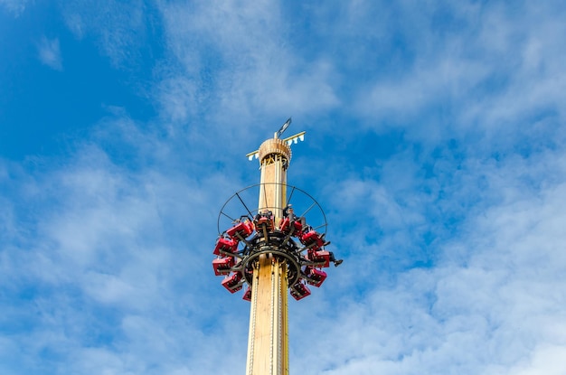 L'attraction est une tour de chute libre avec des gens sur fond de ciel bleu.