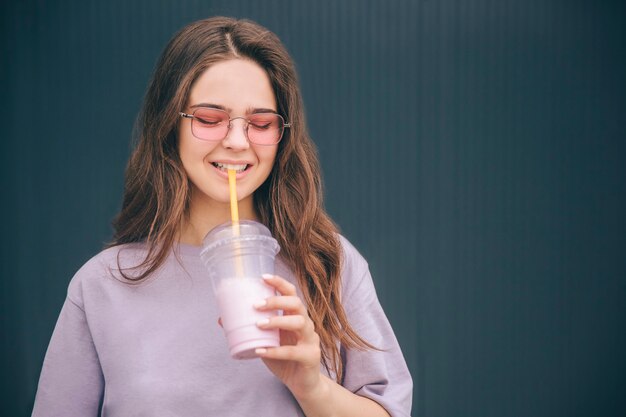 Attractive belle femme buvant un cocktail de lait grâce à la paille en plastique