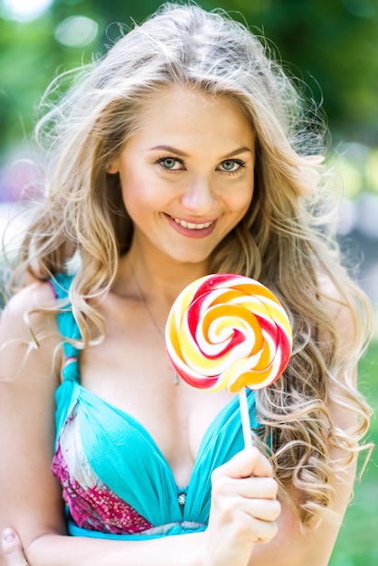 Attractive fille blonde avec un lollipop dans le parc en été