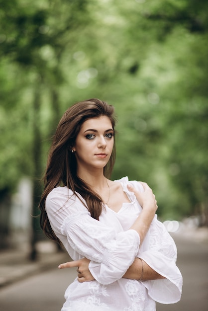 Attractive fille debout dans le parc, habillée en blanc