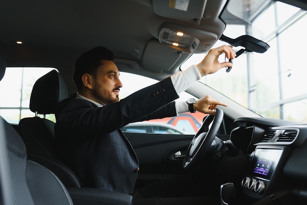 Attractive homme sérieux élégant conduit une bonne voiture