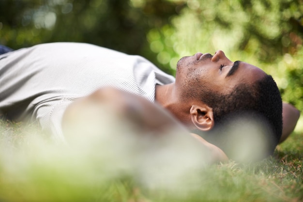 Attraper une sieste à l'extérieur Photo recadrée d'un beau jeune homme allongé sur l'herbe à l'extérieur